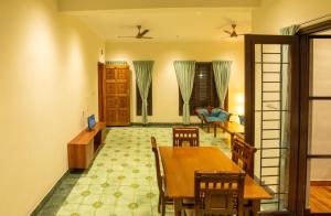 a dining room with a table and chairs and a living room at Nadhima Villas in Kumbakonam +9 photos