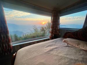 a bed in a room with a large window at Swami Manjulanand Ashram in Mohan Chatti +9 photos
