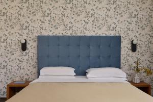 a bed with a blue headboard in a bedroom at Hydra Beach Resort in Thermisía
