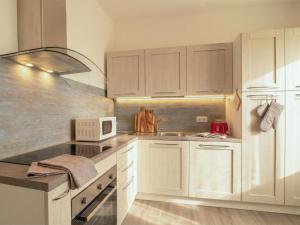 a kitchen with white cabinets and a microwave at Apartment Nuraghi by Interhome in Arzachena +23 photos