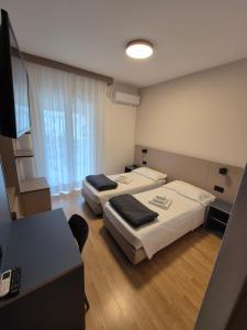 a room with two beds and a desk with a computer at Hotel Helvetia in Grado