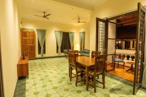 a dining room with a wooden table and chairs at Nadhima Villas in Kumbakonam