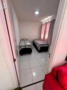 a small room with two beds and a red couch at Refúgio Aconchegante Solares in Petrolina
