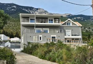 a large white house on the side of a mountain at Zeus Cosmos Apartments in Lourdata