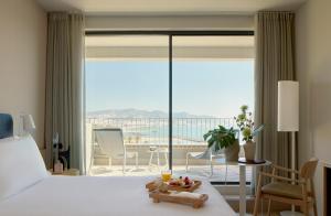 a hotel room with a bed and a large window at ME by Meliá Sitges Terramar in Sitges