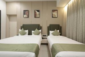two beds in a hotel room next to each other at Hotel Midtown in Surat +44 photos