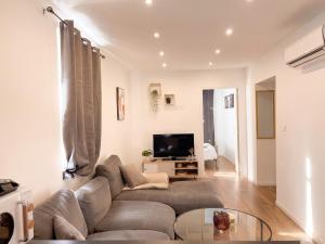 a living room with a couch and a tv at L'Écrin Beige - Moderne - Portes de Strasbourg in Schiltigheim
