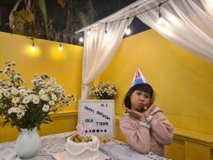 a little girl wearing a birthday hat sitting at a table at Snow Homestay in Ninh Binh
