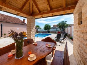 a patio with a wooden table and chairs and a pool at Holiday Home Šimić by Interhome in Dušić