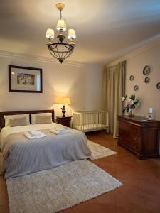 a bedroom with a large bed and a chandelier at Villa Reis - Boutique House in Golegã +26 photos