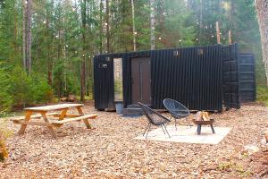 a picnic table and chairs in front of a black shed at PRIVAATNE Metsamajake SAUNAGA "KOHIN" in Sigula +13 photos