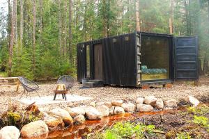 a black tiny house in the middle of a forest at PRIVAATNE Metsamajake SAUNAGA "KOHIN" in Sigula