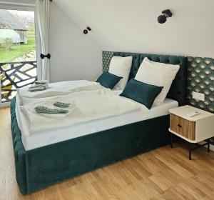 a bed with a green headboard and pillows on it at Królowa Beskidu in Słopnice