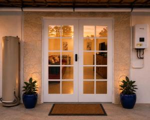 a white door with two potted plants in front of it at Kookaburra Guesthouse in Coffs Harbour