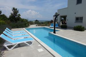 a swimming pool with two lounge chairs next to a house at Villa Mare in Ližnjan