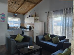 a living room with two chairs and a kitchen at Sea Wave Cottage in Pearly Beach