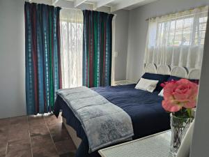 a bedroom with a blue bed and a vase with a flower at Sea Wave Cottage in Pearly Beach
