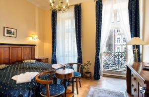 ein Schlafzimmer mit einem Bett, einem Tisch und Stühlen sowie einem Fenster in der Unterkunft Salvator Hotel in Karlsbad