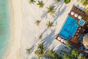 an overhead view of a resort on a beach with palm trees at OUTRIGGER Maldives Maafushivaru Resort in Dhangethi