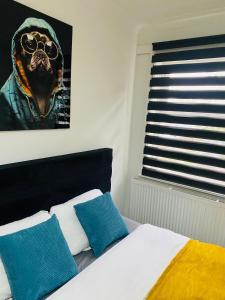 a bed with two blue pillows and a picture of a dog at Lovely studio centrally located in Peterborough +6 photos