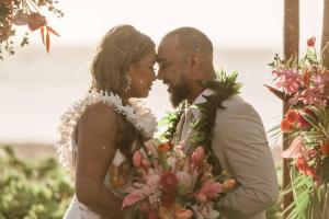 a bride and groom are kissing in front of flowers at OUTRIGGER Kāʻanapali Beach Resort in Lahaina +291 photos