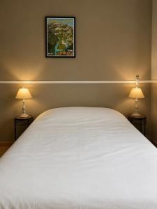 a bedroom with a large white bed with two lamps at Le Grand Hotel Restaurant in Aups