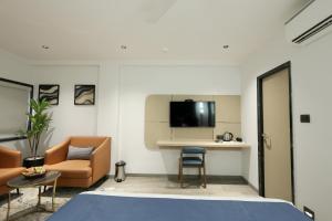 a room with a bed and a couch and a table at Hotel Midtown in Surat