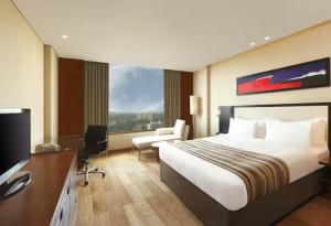 a hotel room with a bed and a desk and a television at DoubleTree by Hilton-Pune Chinchwad in Pune