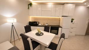 a kitchen with a white table and chairs and a kitchen with white cabinets at Luxury Apartment Paraćin - River View in Paraćin