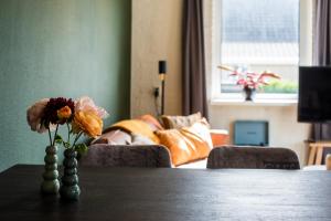 a table with a vase of flowers on a table at Strandweg Appartement in Buren