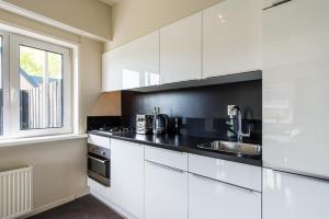 a kitchen with white cabinets and a sink and a window at Strandweg Appartement in Buren
