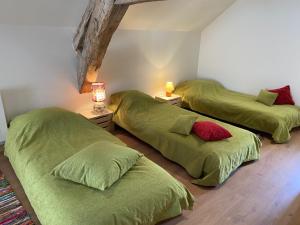 three beds in a room with green sheets at Gite Simon in Guillon