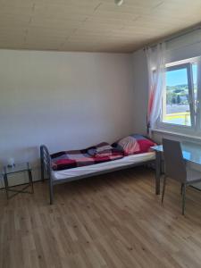 a bedroom with a bed and a table and a window at Haus Tanja in Neckarbischofsheim