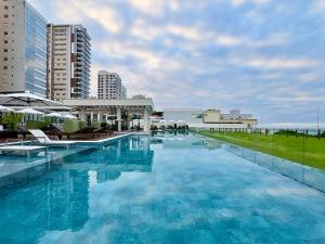 a large pool of blue water with buildings in the background at Apartamento em Condomínio Frente-Mar com Piscinas, Jacuzzi Aquecida, Sauna, Academia, Brinquedoteca, Churrasqueira na Sacada, Cozinha Completa in Piçarras