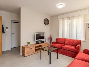 a living room with a red couch and a television at Holiday Home Mimi by Interhome in Verceia