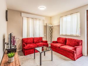 a living room with two red couches and a table at Holiday Home Mimi by Interhome in Verceia