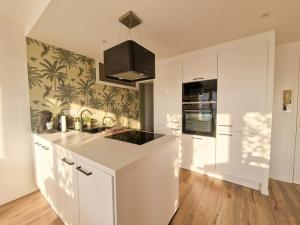 a kitchen with white cabinets and a black island at Liv'in Saint Seb, proche de Nantes in Saint-Sébastien-sur-Loire
