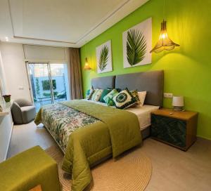 a bedroom with green walls and a bed and a table at Maison Bella View in Moulay Bousselham +3 photos