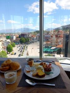 a plate of food on a table with a view of a city at Rise And Shine Rooms Korca in Korçë