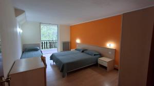a bedroom with two beds and an orange wall at Hotel Paolino in Cavareno