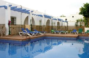 a swimming pool with blue chairs and a fence at Hotel Marazul in Mojácar