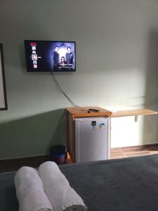 a room with a tv on the wall and a refrigerator at pousada da Serra PETAR in Iporanga