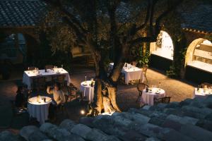 a couple sitting at tables under a tree at night at Finca Victoria, a Member of Design Hotels in Begur