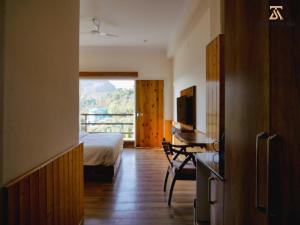 a bedroom with a bed and a desk and a television at The Stone Age : a boutique hotel in Shimla