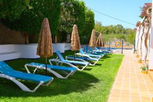a row of lounge chairs and umbrellas on the grass at Hotel Marazul in Mojácar