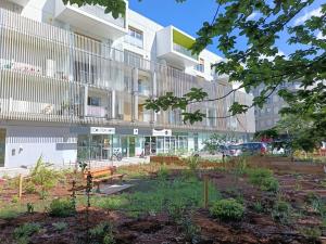 an apartment building with a garden in front of it at Studio avec parking gratuit in Cenon