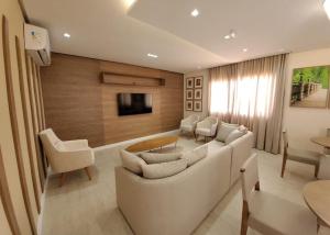 a living room with a white couch and a tv at Smart Pituba Studio Premium in Salvador