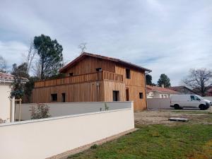 a wooden barn in a yard with a white fence at maison wave in Léon