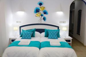 a bedroom with a large bed with blue and white pillows at Hotel Marazul in Mojácar