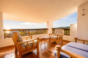 a bedroom with a bed and chairs and a balcony at ALBA - Seaview Luxury in San Teodoro